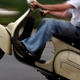 A man pops a wheelie on a scooter, a type of motorcycle that is similar to but distinct from a moped.